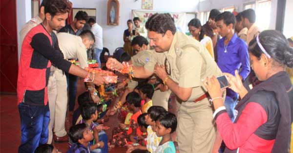 बच्चो को राखी बांधते और मिठाई बांटते थाना प्रभारी सुबीर कुमार चौधुरी