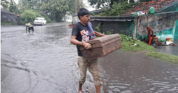 घर में पानी भर जाने के कारण घर के सामन को सुरक्षित ठिकाने पर ले जाता एक व्यक्ति